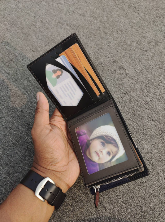 Hand holding an open black wallet with photo sleeves on a gray surface